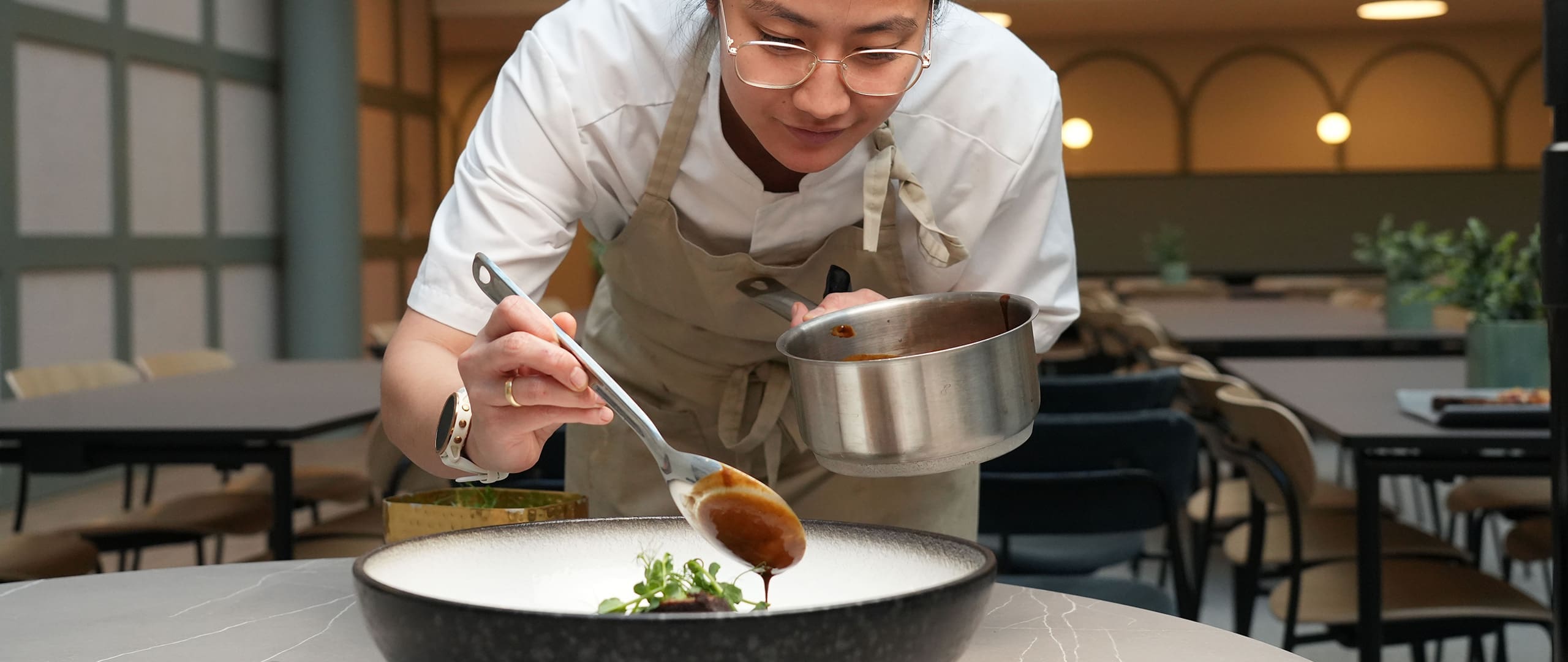 Kokk som legger opp mat, fotografert for Vækst Kantine og Catering